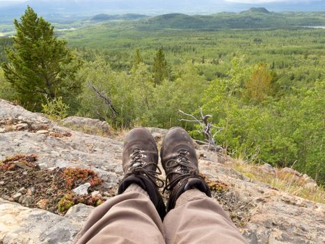 Tired hiker taking a rest from hiking overlooking rocky terrain and beautiful scenery in boreal forest taiga just north outside Whitehorse, Yukon Territory, Canada