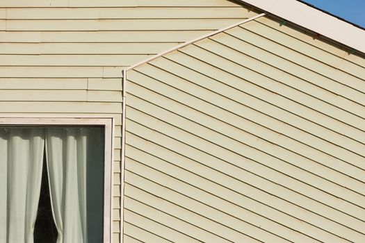 Exterior of a timber clad building architectural abstract showing a portion of a curtained window and the pitch of the roof with an angled segment of cladding following the facade