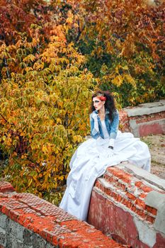 Beautiful bride in wedding dress and denim jacket in autumn park