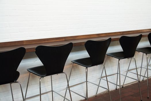 Modern designer minimalistic style chairs in line opposite a white wall                               