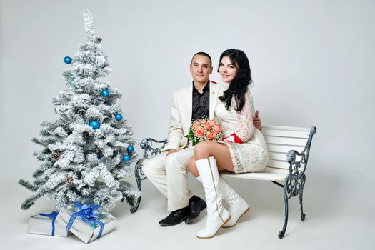 Young loving married couple near Christmas tree with gifts