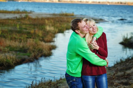 Young couple tenderly and lovingly embrace each other on banks of river