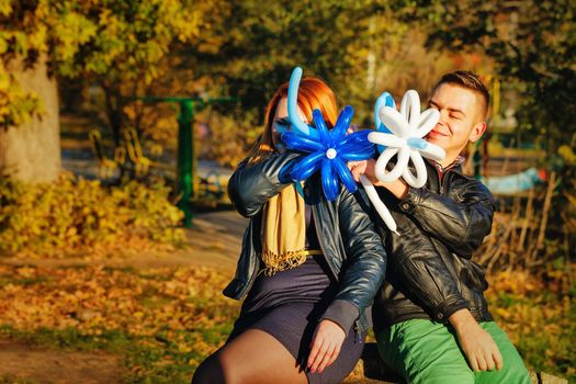 Couple playing with balloons in autumn park on a sunny day