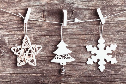 White christmas decorations attached to the rope, over wooden background