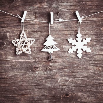 White christmas decorations attached to the rope, over wooden background