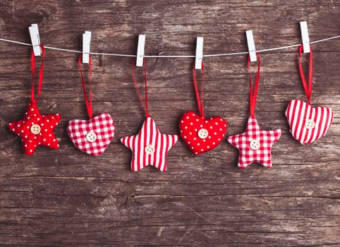 White and red sewed christmas decor attached to the rope, over wooden background