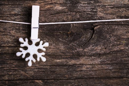 White snowflake decoration attached to the rope, over wooden background