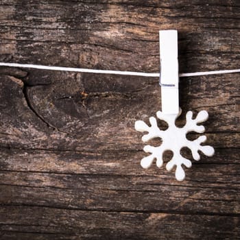 White snowflake decoration attached to the rope, over wooden background