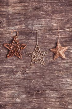 Brown christmas decorations attached to the rope, over wooden background