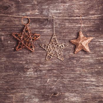 Brown christmas decorations attached to the rope, over wooden background
