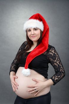 beautiful smiling pregnant young santa woman tenderly holding her tummy