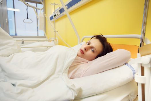 Real people in real situation, sad middle-aged woman lying in hospital with pneumonia
