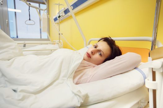 Real people in real situation, sad middle-aged woman lying in hospital with pneumonia