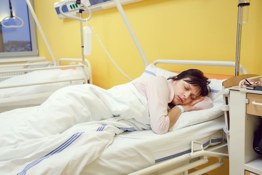 Real people in real situation, sad middle-aged woman lying in hospital with pneumonia