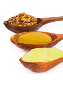 Wooden Spoons with Honey, Dijon and Whole Grain Mustards In a Row on white background