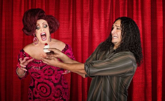 Nervous man holding cupcake for excited man in drag