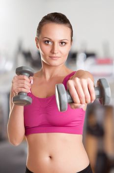 Woman working out with dumbbells at a gym