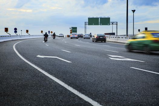 moving passenger car and motorcycle on bridge way crossing junction with blue sky background