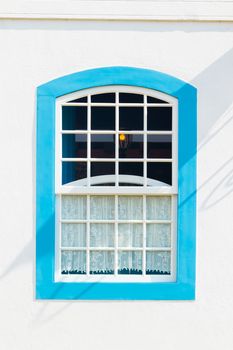 Decorative, colonial, blue, vintage, window on a white wall in Paraty (or Parati), Brazil.