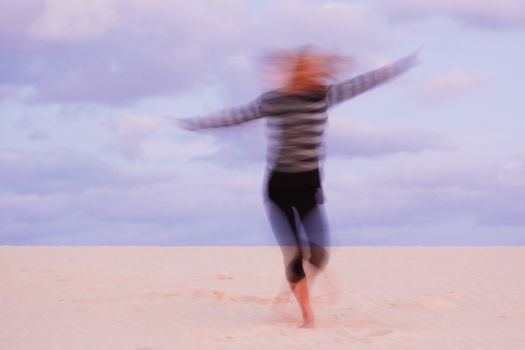 Girl having fun on her vatations, swirling at the sand dune.