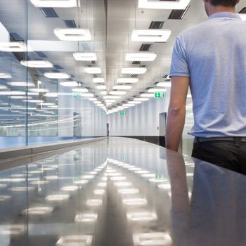 Business travelers  walking along contemporary illuminated airport terminal hall.