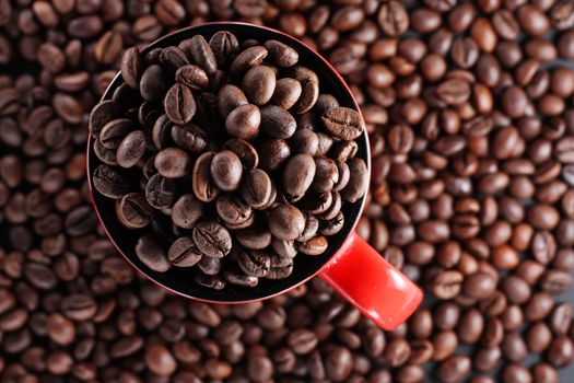 Red cup full of roasted brown coffee beans