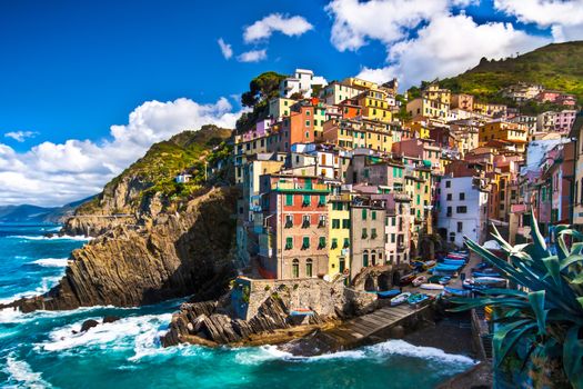 Riomaggiore fisherman village in a dramatic windy weather. Riomaggiore is one of five famous colorful villages of Cinque Terre in Italy, suspended between sea and land on sheer cliffs upon the  turquoise sea.