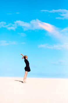 Beautifull girl playing with the sand on the dune.