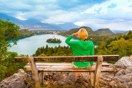 Traveler enjoying the panoramic view of Julian Alps, Lake Bled with St. Marys Church of the Assumption on the small island; Bled, Slovenia, Europe.