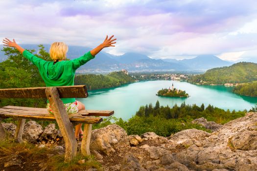 Traveler enjoying the sunset panoramic view of  Julian Alps, Lake Bled with St. Marys Church of the Assumption on the small island; Bled, Slovenia, Europe.