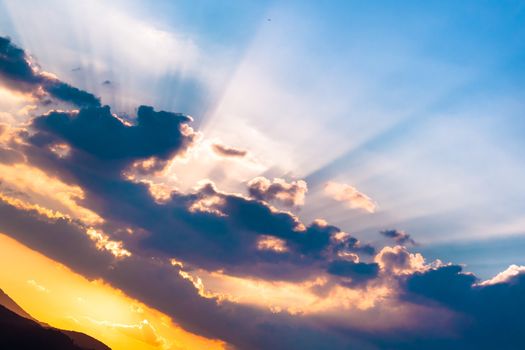 Sunset / sunrise with clouds, light rays and other atmospheric effect over the hills and mountains in Slovenia, Europe.