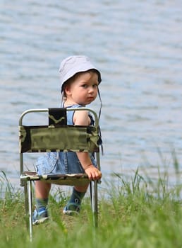 Little boy sitting near the lake