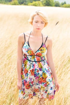 A portrait of a casual dressed beautiful young Caucasian woman outdoor in the meadow on a sunny summer day.