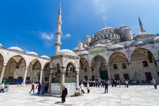 ISTANBUL - MAY 7: Tourists and prayers mixing at courtyard of Blue mosque on May 7, 2013 in Istanbul, Turkey; While still used as a mosque, the Sultan Ahmed Mosque has also become a popular tourist attraction.