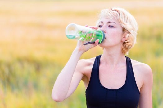 Lady drinking from the bottle during outdoor activities.