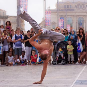 MONTPELLIER - JULY 12: Street performer breakdancing in front of the random crowd on July 12, 2011 in  Montpellier, France; B-boying or breaking is a style of street dance that originated among African American and Puerto Rican youths in New York City during the early 1970s.