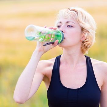 Lady drinking from the bottle during outdoor activities.