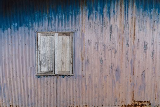 Old rusty house with closed wooden shutters; can be used as a graphical background.