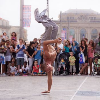 MONTPELLIER - JULY 12: Street performer breakdancing in front of the random crowd on July 12, 2011 in  Montpellier, France; B-boying or breaking is a style of street dance that originated among African American and Puerto Rican youths in New York City during the early 1970s.