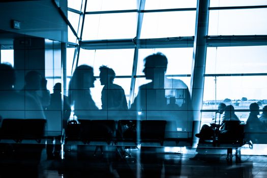 Silhouettes of business people traveling on airport; waiting at the plane boarding gates.