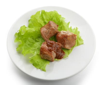 Three pieces of roasted meat with fresh lettuce and tomato sauce on the white plate