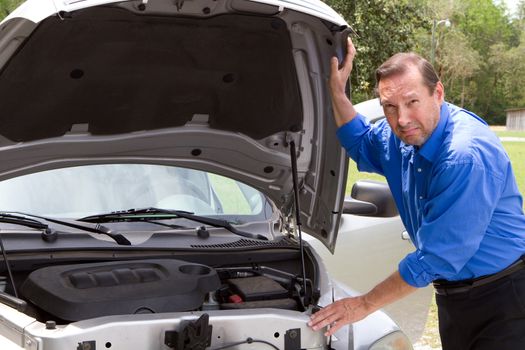 Senior adult man with a look of dismay on his face as he stands by his disabled car that needs repair.