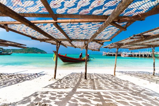 Traditional squids drying in the sun and thai fisherman long tail boat in a idyllic fishermen village; Thailand, Asia.