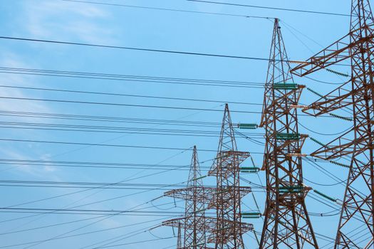 High-voltage power transmission towers in clear blue sky background.