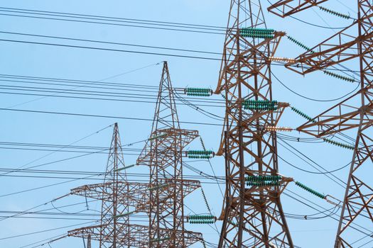 High-voltage power transmission towers in clear blue sky background.