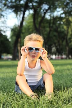 Little boy looking through the sunglasses in th park