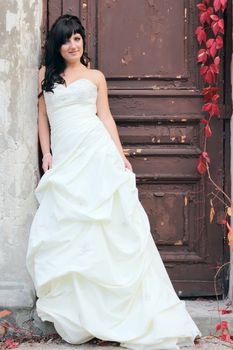 Young beautiful girl in the wedding dress near the door