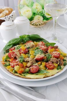 Omelet with vegetables and slices of bacon and cheese with basil