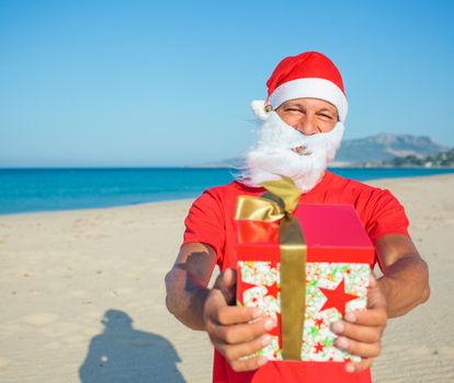 Young men in Santa hat with gift on tropical vacation
