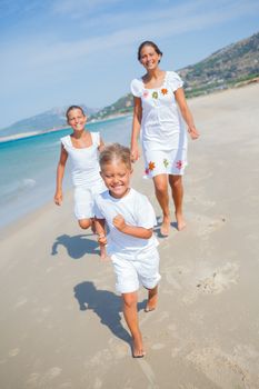 Adorable happy boy with his sisters running on beach vacation